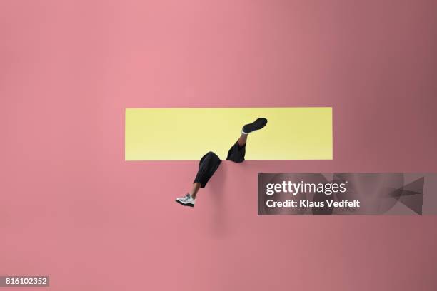 womans legs sticking out of rectangular opening in coloured wall and looking up - pink shoe stock-fotos und bilder