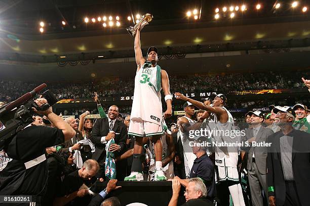 Paul Pierce of the Boston Celtics celebrates while holding the Larry O'Brien Championship Trophy alongside head coach Doc Rivers and teammates Ray...