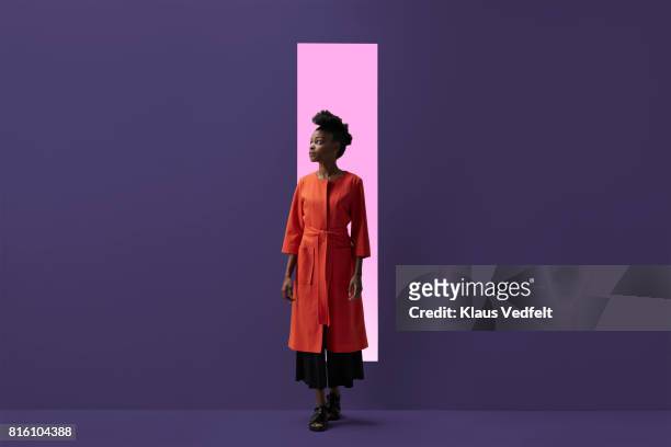 woman coming out of rectangular opening in coloured wall - portrait studio purple background stock pictures, royalty-free photos & images
