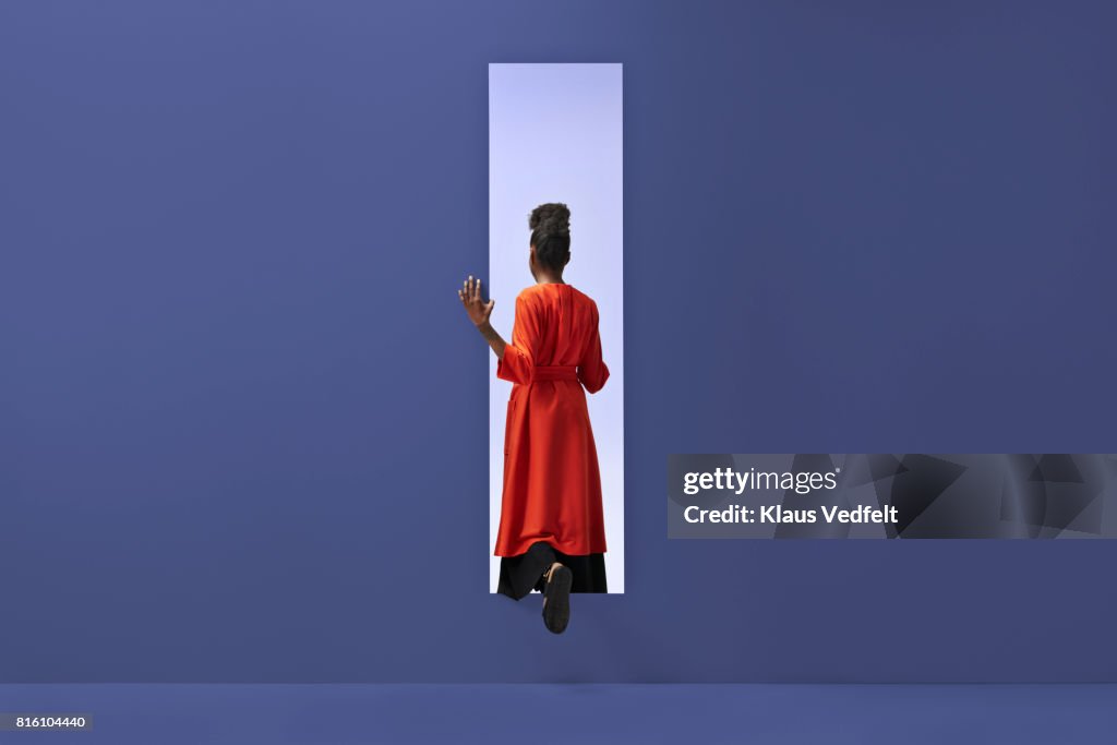 Woman walking into rectangular opening in coloured wall