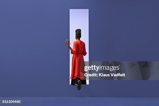 Woman walking into rectangular opening in coloured wall Woman walking into rectangular opening in coloured wall
