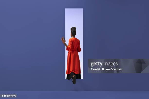 woman walking into rectangular opening in coloured wall - red dress imagens e fotografias de stock