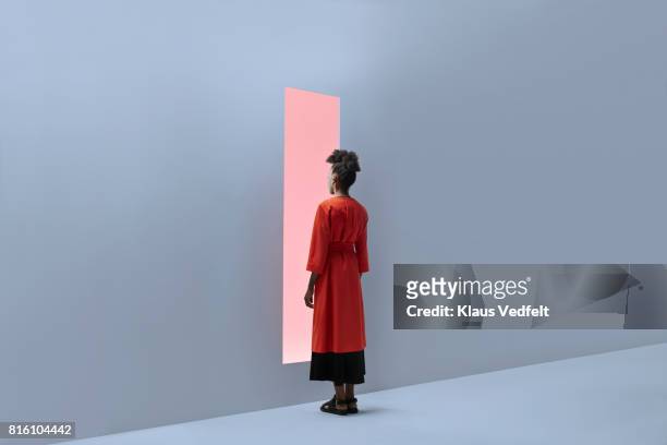 woman standing in front of rectangular opening in coloured wall - entscheidung stock-fotos und bilder