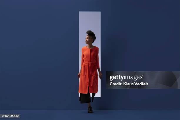 woman coming out of rectangular opening in coloured wall - expectations foto e immagini stock