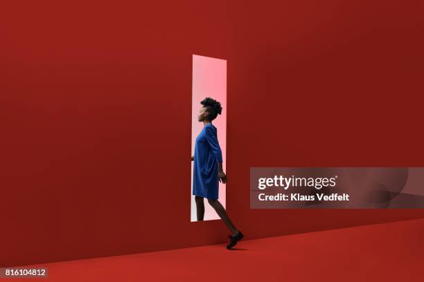 woman walking threw rectangular opening in coloured wall - porta de entrada imagens e fotografias de stock