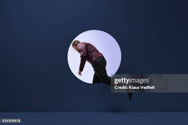 man stepping threw round opening in coloured wall - on the way stockfoto's en -beelden