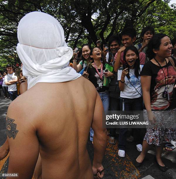 Spectators take pictures while some 100 nude members of the Alpha Phi Omega fraternity run during a traditional 'oblation run at the University of...