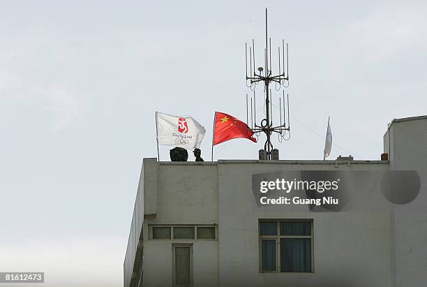 Chinese polemen keep an eye from the roof of a building during the closing ceremony of the Olympic Torch Relay, Xinjiang Province leg, at People's...