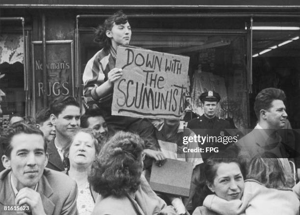 Member of the public shows her disapproval of a Communist-sponsored May Day Parade in New York City, with a handwritten 'Down with the Scumunists'...