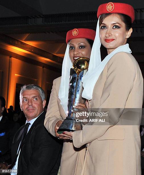 International Cricket Council acting chief executive Dave Richardson looks at the Champions Trophy carried by Emirates Airlines air hostesses during...