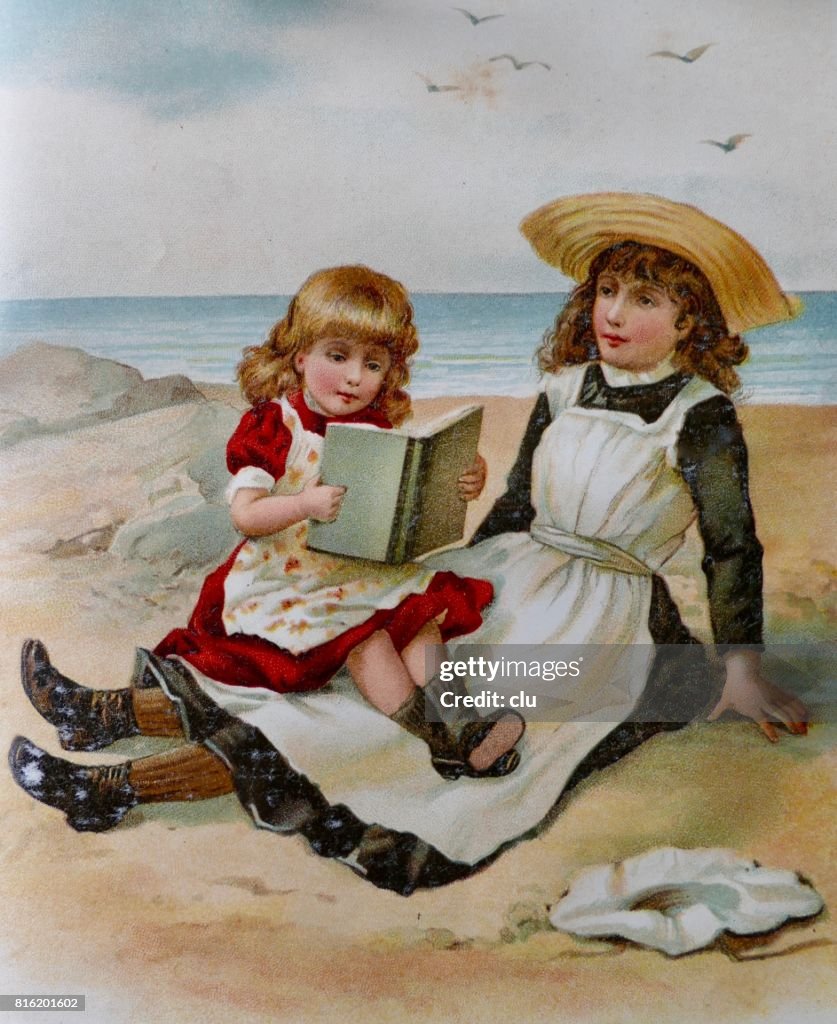 Dos niñas sentadas en la playa leyendo un libro