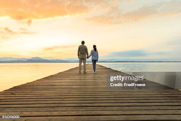 romantic couple on wooden jetty looking over the lake - garda stock pictures, royalty-free photos & images