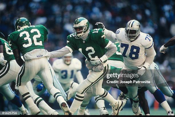 Quarterback Randall Cunningham of the Philadelphia Eagles hands off to running back Ricky Watters against the Dallas Cowboys at Texas Stadium in the...