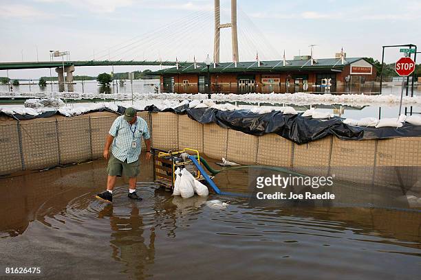 Hal Geren steps back from a sump pump after starting it up to move water that is flowing from the Mississippi River under a makeshift wall June 18,...