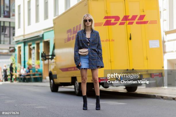 Lisa Hahnbueck infront of a DHL truck wearing a checked Balenciaga men button shirt, a beige Chloe belt bag, a denim mini skirt, Dior ankle boots,...