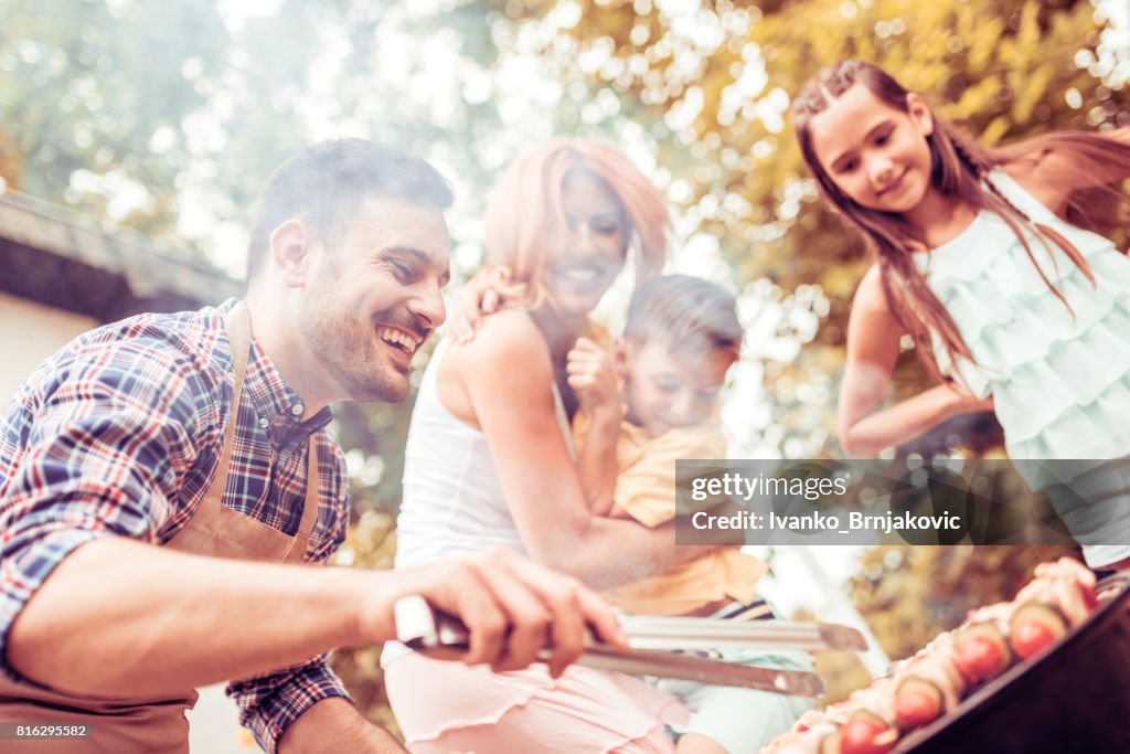 Happy young family barbecuing meat on the grill
