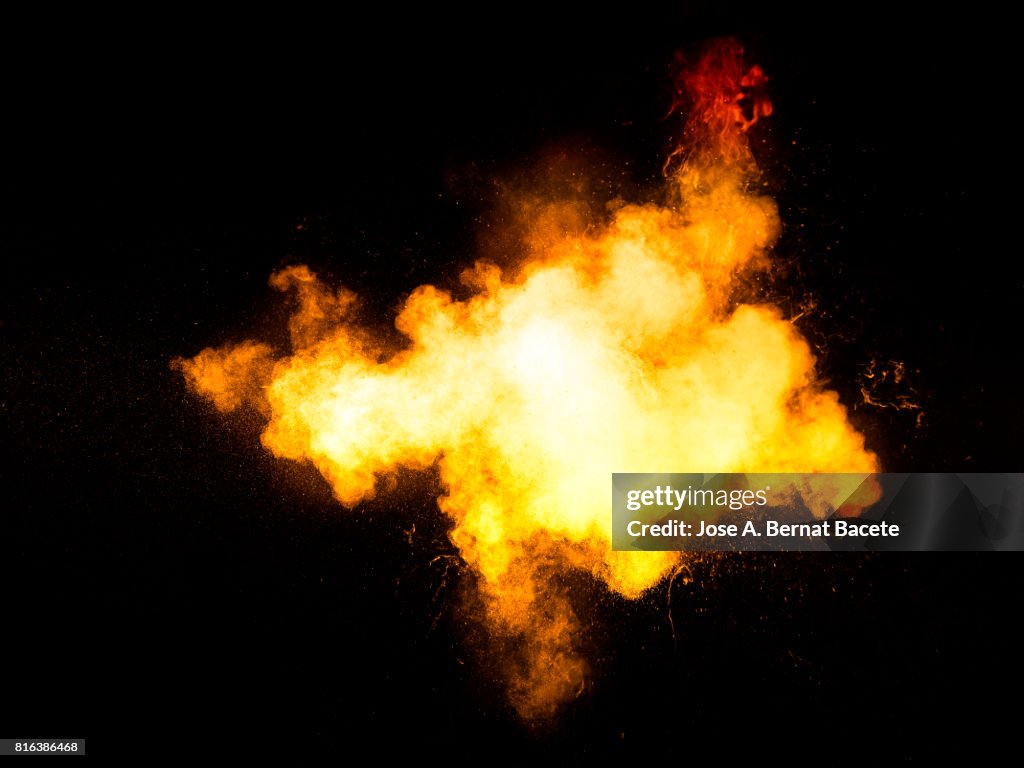 Forms and textures of an explosion of a powder of colors yellow an white on a black background