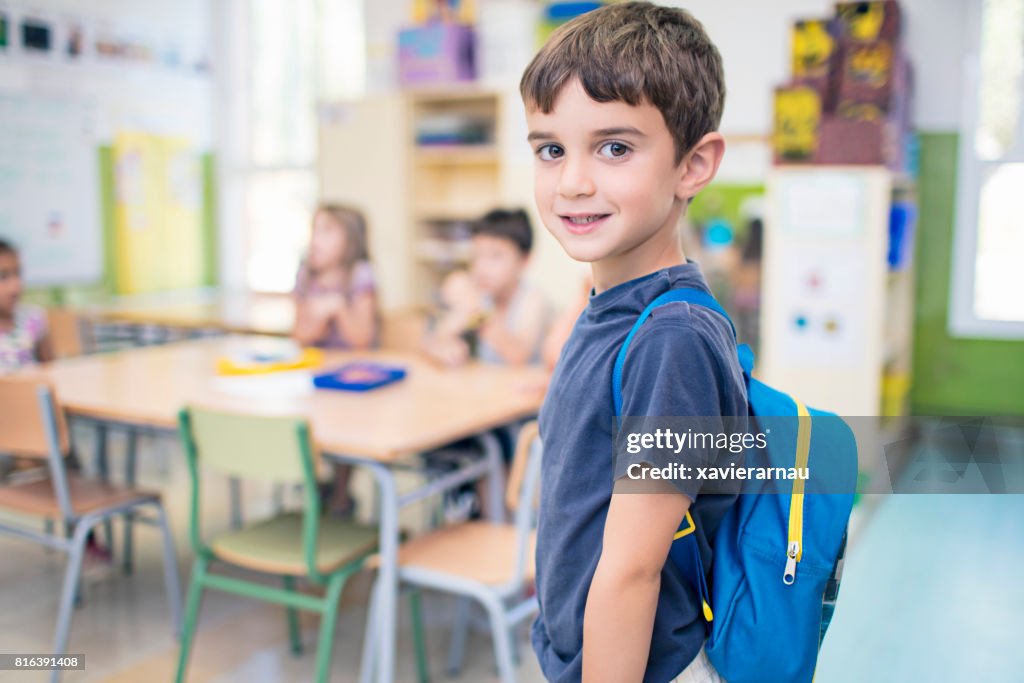 Écolier mignon transport sac à dos en salle de classe