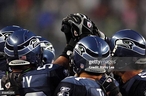 Seattle Seahawks secondary players wearing Reebok NFL Equipment gloves join hands in a huddle before NFC Wild Card Playoff game against the Dallas...