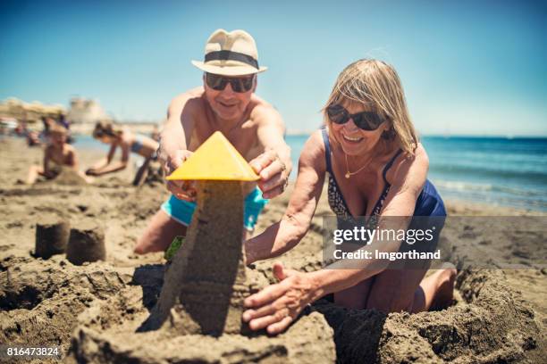 heureux couple senior jouant dans le sable sur la plage - couple de vieux drole photos et images de collection