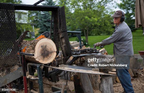 Robert Marble uses a hydraulic chain saw to cut firewood logs June 29, 2017 on his converted dairy farm in Charlotte, Vermont. Marble is a firewood...