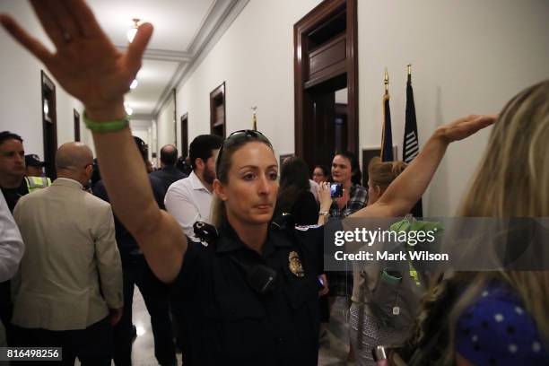 Capitol Police officer pushes back a crowd of pretesters outside the office of Sen. Rob Portman inside the Russell Senate Office Building, on July...