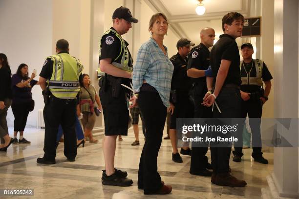Capitol Police officers walk with protesters arrested near the office of Sen. Mitch McConnell in the Russell Senate Office Building on July 17, 2017...