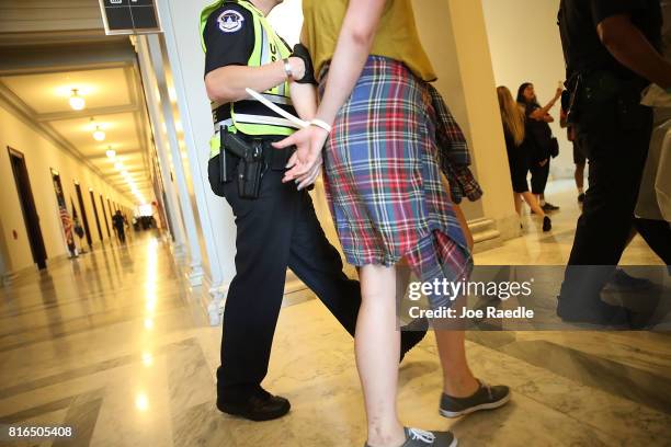 Capitol Police officer walks with a health care protester that was arrested near the office of Sen. Mitch McConnell in the Russell Senate Office...