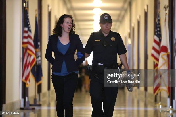 Capitol Police officer walks with a health care protester that was arrested near the office of Sen. Mitch McConnell in the Russell Senate Office...