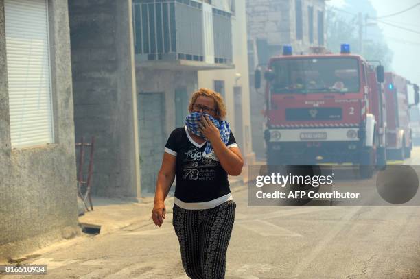 Woman covering her face with a cloth walks through the streets during a fire in the village of Gornje Sitno, near the Adriatic coastal town of Split,...