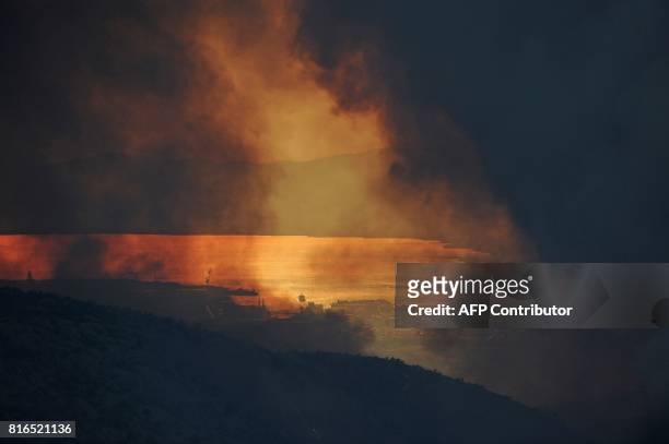 Smoke clouds billow out over the village of Gornje Sitno, near the Adriatic coastal town of Split, during a fire on July 17, 2017. Montenegro asked...