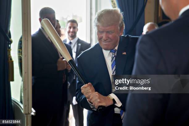 President Donald Trump holds a baseball bat while participating in a Made in America event, with companies from 50 states featuring their products,...