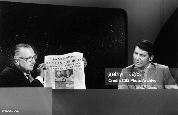 Anchor Walter Cronkite holds up The New York Times during the Apollo 11 telecast, July 20, 1969 at 10:11 PM. At right is Wally Schirra.