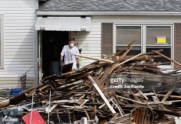 Man tosses wood onto a pile as they gut a home after the Iowa River inundated the house with flood waters June 21, 2008 in Cedar Rapids, Iowa. The...