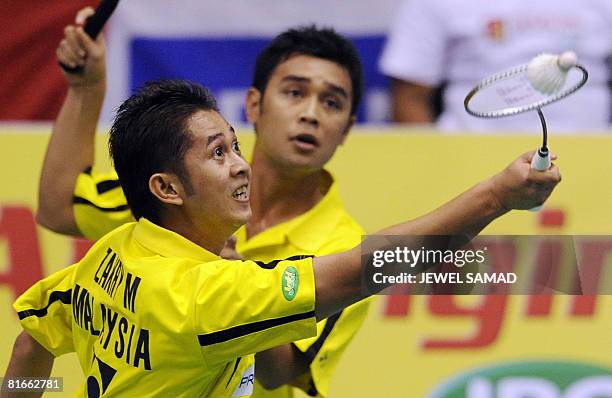 Zakry Abdul Latif of Malaysia returns the shuttlecock as his teammate Fairuzizuan Mohammd Tazari looks on during their men's double final match of...