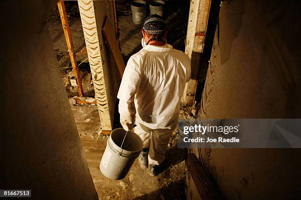 Dan Schirm helps clean up the basement of his friends home after the Cedar River inundated it with flood waters June 22, 2008 in Cedar Rapids, Iowa....