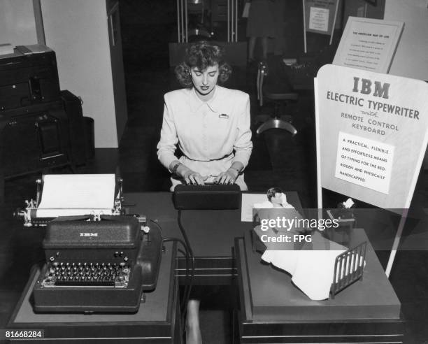 Young woman demonstrating an IBM electric typewriter with a keyboard extension intended for use by handicapped or bedridden people, at the National...