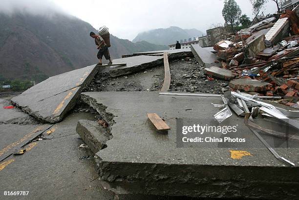 Young earthquake survivor carrying a boiler walks on a broken road on June 22, 2008 in Beichuan County of Sichuan Province, China. The evacuated...