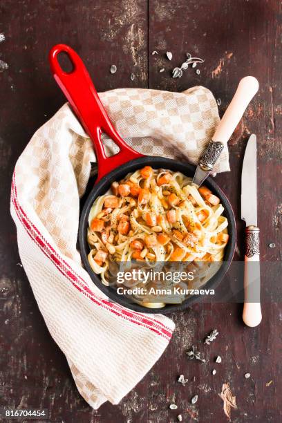 homemade noodles with roasted salmon or trout fish, cream sauce, pine nuts and herbs in a pan on a wooden table, selective focus - redfish stock-fotos und bilder