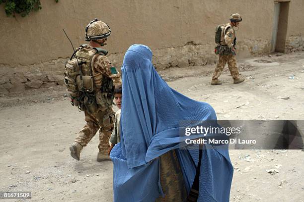 Woman in a burqa and a child walk past two British paratroopers from 3rd Battalion The Parachute Regiment on patrol on June 21, 2008 in Kandahar,...