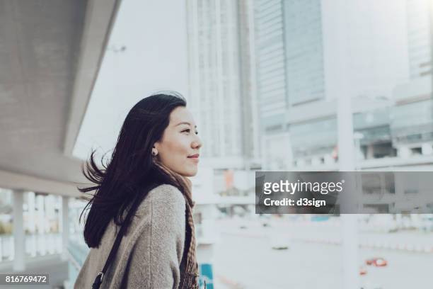 beautiful young asian lady overlooking cityscape of hong kong on urban bridge - prosperity stock pictures, royalty-free photos & images