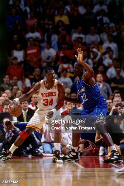 Hakeem Olajuwon of the Houston Rockets moves the ball against Shaquille O'Neal of the Orlando Magic in Game Four of the 1995 NBA Finals at the...