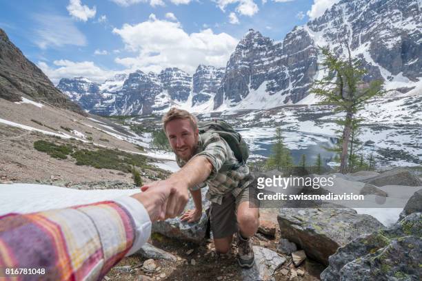 wanderer hilft teamkollegen auf mountain top-männer - confidence male landscape stock-fotos und bilder