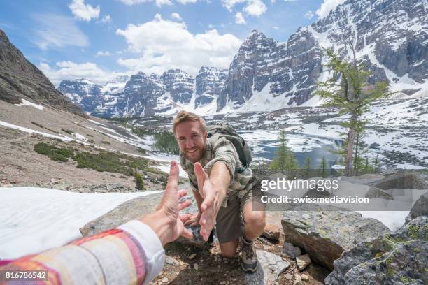 wanderer hilft teamkollegen auf mountain top-männer - confidence male landscape stock-fotos und bilder
