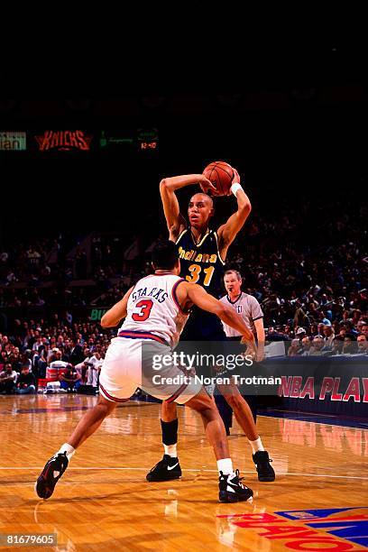 Reggie Miller of the Indiana Pacers looks to pass against John Starks of the New York Knicks in Game One of the Eastern Conference Semifinals during...