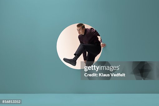 Man stepping threw round opening in coloured wall Man stepping threw round opening in coloured wall