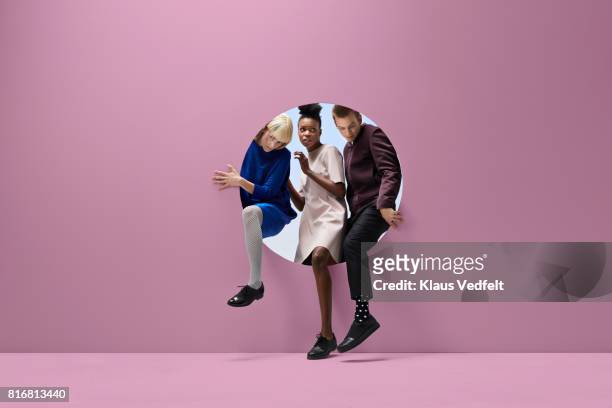 three people crawling out of round opening in coloured wall - 3 circles ストックフォトと画像