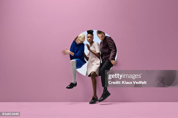 three people crawling out of round opening in coloured wall - appearance imagens e fotografias de stock