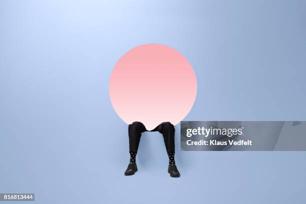 businesmans legs are dangling from round opening in coloured wall - change socks stockfoto's en -beelden