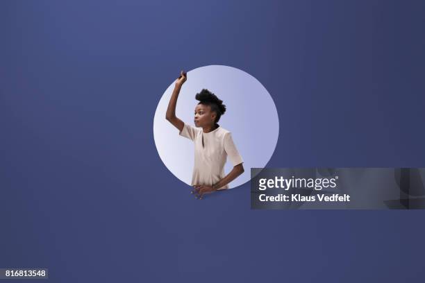 woman placed inside round opening in coloured wall - changing appearance photos et images de collection